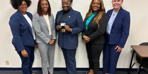 A newly graduated agent stands with agency leadership after completing the Criminal Justice Academy.